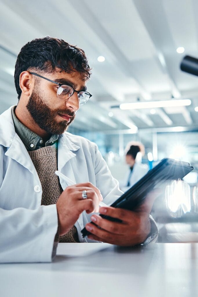 Male chemist writing on tablet in a lab